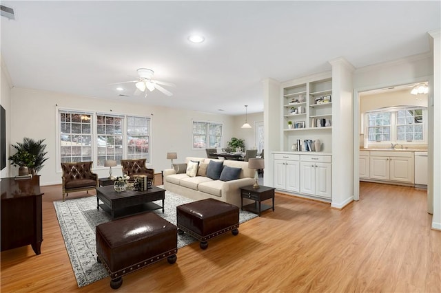 living room with light hardwood / wood-style floors, ceiling fan, and ornamental molding