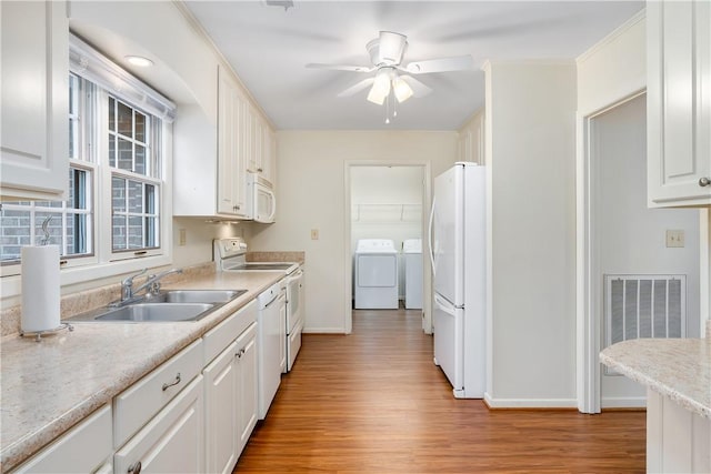 kitchen with sink, light hardwood / wood-style flooring, independent washer and dryer, white appliances, and white cabinets