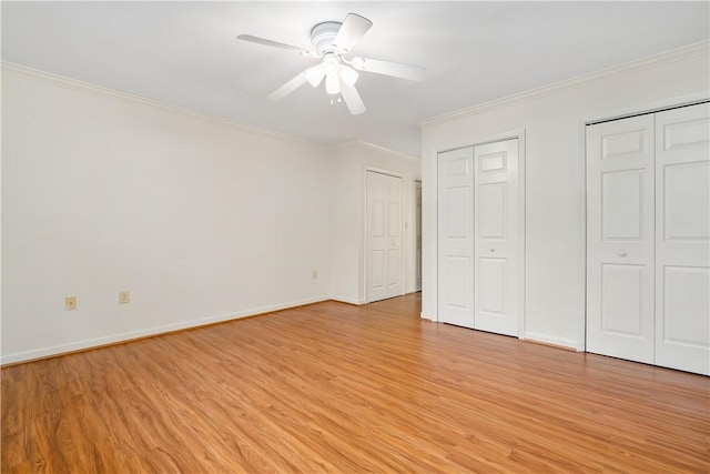 unfurnished bedroom featuring light wood-type flooring, two closets, ceiling fan, and ornamental molding