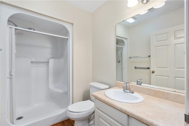 bathroom with wood-type flooring, vanity, toilet, and walk in shower