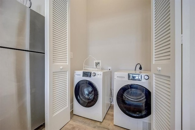 laundry area featuring washer and dryer and light wood-type flooring