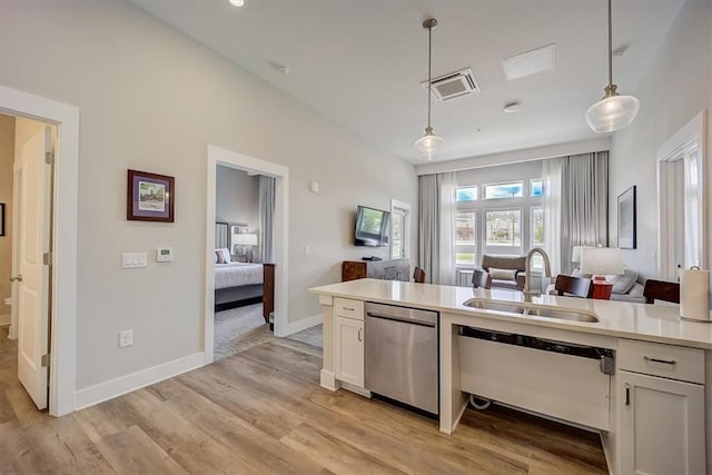 kitchen featuring dishwashing machine, sink, decorative light fixtures, dishwasher, and white cabinetry