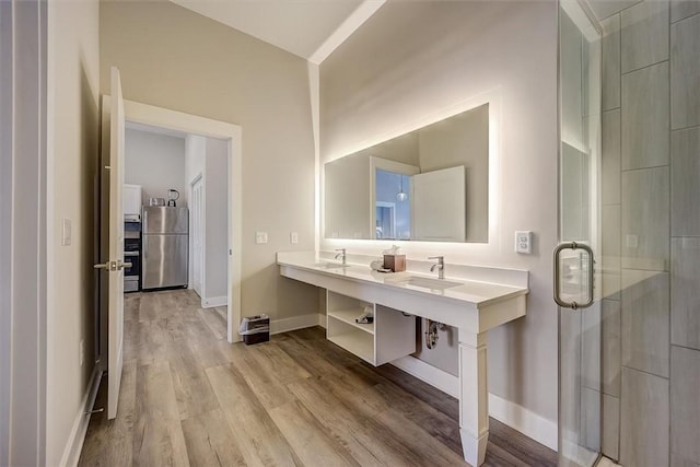 bathroom featuring hardwood / wood-style flooring, a shower with door, and sink