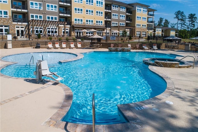 view of swimming pool with pool water feature, a patio, and a hot tub