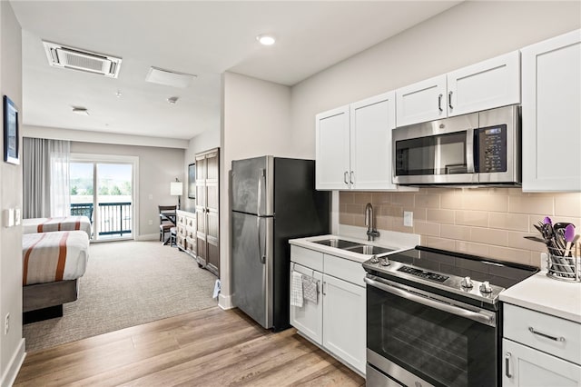 kitchen featuring white cabinets, sink, decorative backsplash, appliances with stainless steel finishes, and light hardwood / wood-style floors