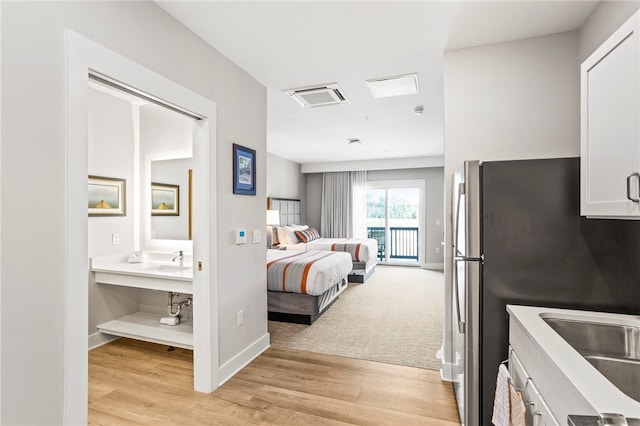 bedroom featuring stainless steel fridge, light hardwood / wood-style floors, and sink