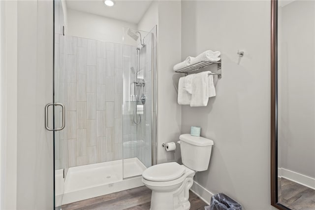 bathroom with hardwood / wood-style floors, toilet, and an enclosed shower