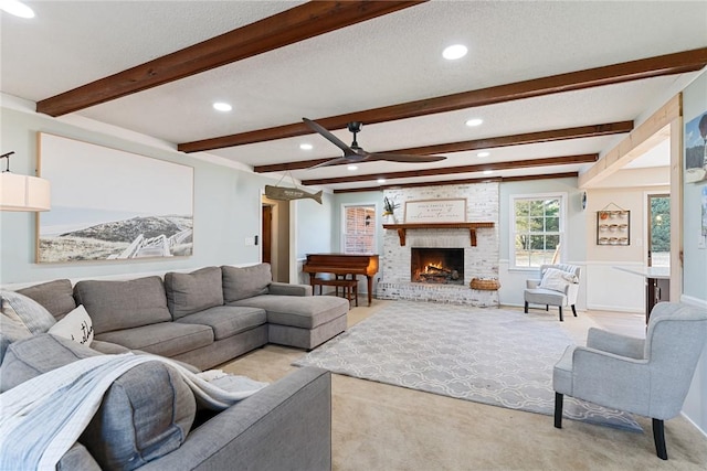 living room featuring beamed ceiling, a textured ceiling, light colored carpet, and a fireplace