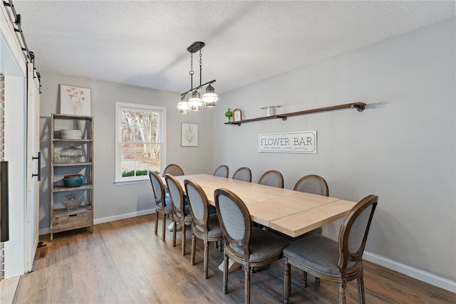 dining area featuring a barn door, dark wood-type flooring, and a textured ceiling