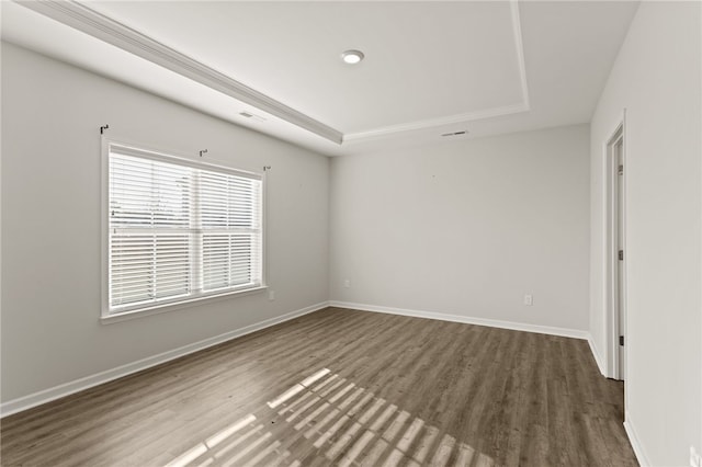 spare room with dark hardwood / wood-style flooring and a raised ceiling