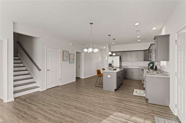 kitchen with hanging light fixtures, a kitchen island, stainless steel appliances, and wood-type flooring