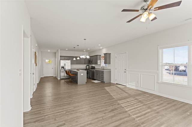 kitchen with appliances with stainless steel finishes, a center island, light hardwood / wood-style floors, and hanging light fixtures