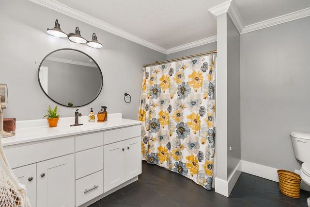 bathroom with tile patterned floors, vanity, toilet, and ornamental molding