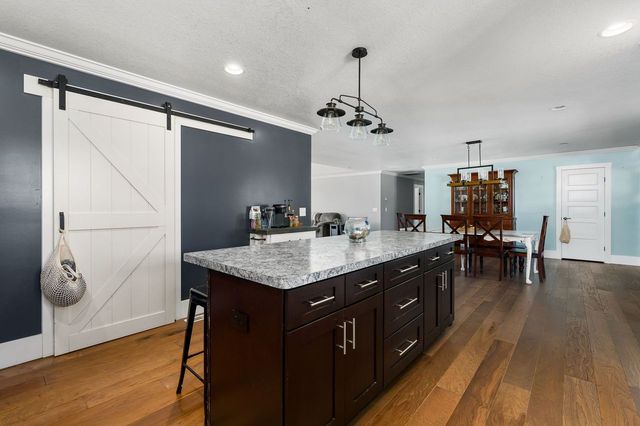 kitchen with hanging light fixtures, a barn door, a kitchen bar, dark brown cabinets, and a kitchen island