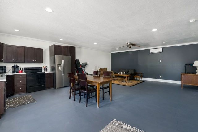 dining space with concrete flooring, a wall mounted AC, ceiling fan, and ornamental molding