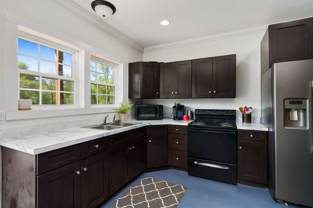 kitchen featuring dark brown cabinets, sink, and black appliances