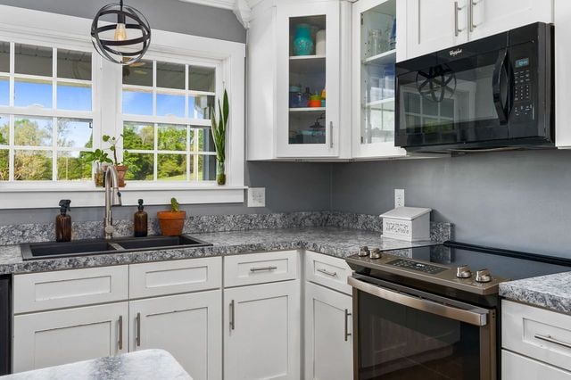 kitchen featuring sink, white cabinets, and black appliances