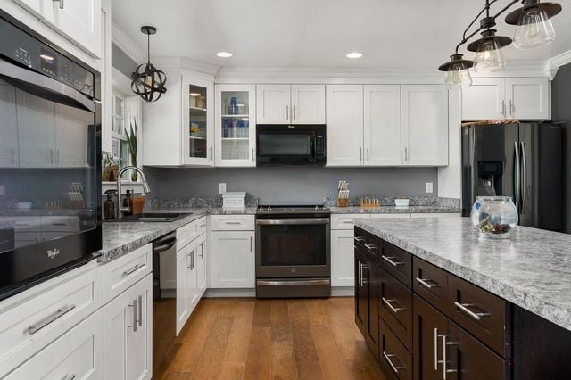 kitchen with black appliances, white cabinets, sink, hanging light fixtures, and dark hardwood / wood-style floors