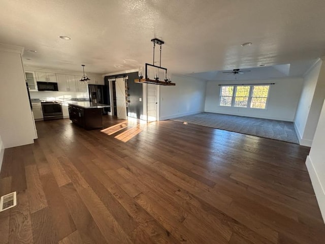 unfurnished living room featuring ceiling fan, crown molding, and dark hardwood / wood-style floors