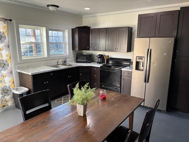 kitchen featuring dark brown cabinets, stainless steel fridge, range with electric stovetop, and sink