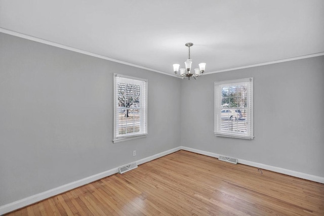 spare room with crown molding, a chandelier, and light hardwood / wood-style floors