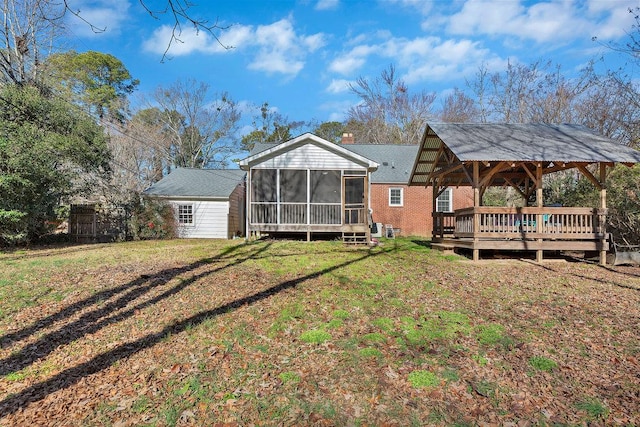 rear view of house with a wooden deck, a sunroom, a gazebo, and a yard