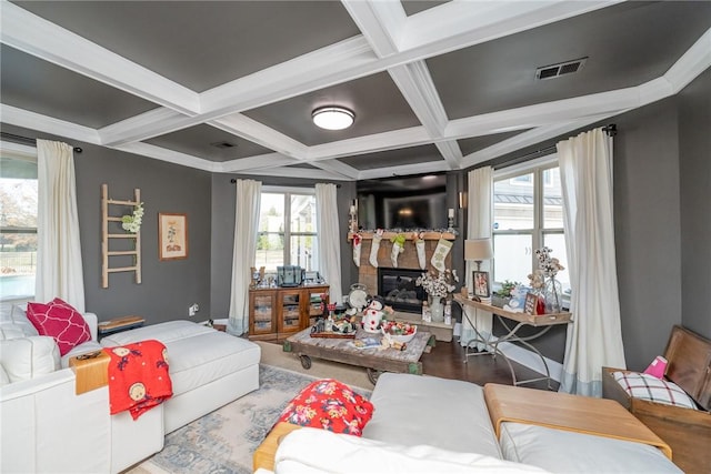 living room with coffered ceiling, beamed ceiling, hardwood / wood-style floors, a fireplace, and ornamental molding