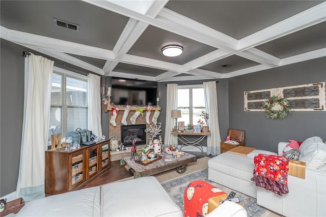 living room with beam ceiling, a stone fireplace, and coffered ceiling