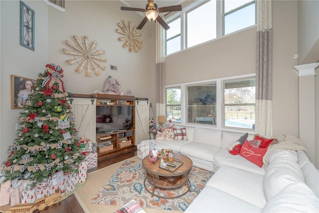 living room with hardwood / wood-style floors, ceiling fan, a high ceiling, and a wealth of natural light