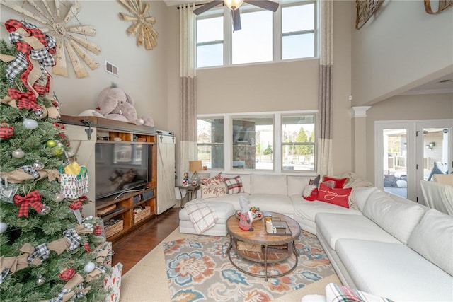 living room with ceiling fan, a towering ceiling, dark wood-type flooring, and a wealth of natural light