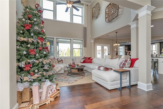 living room featuring plenty of natural light, ceiling fan with notable chandelier, dark hardwood / wood-style floors, and ornamental molding