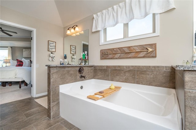 bathroom with ceiling fan, a tub, and vaulted ceiling