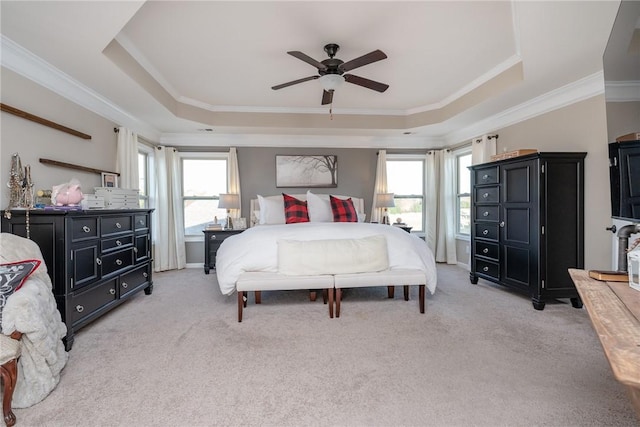 carpeted bedroom with a tray ceiling, ceiling fan, and crown molding