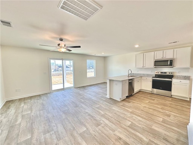 kitchen featuring ceiling fan, appliances with stainless steel finishes, white cabinetry, kitchen peninsula, and light wood-type flooring