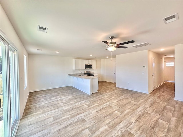 kitchen featuring appliances with stainless steel finishes, white cabinetry, sink, kitchen peninsula, and light wood-type flooring