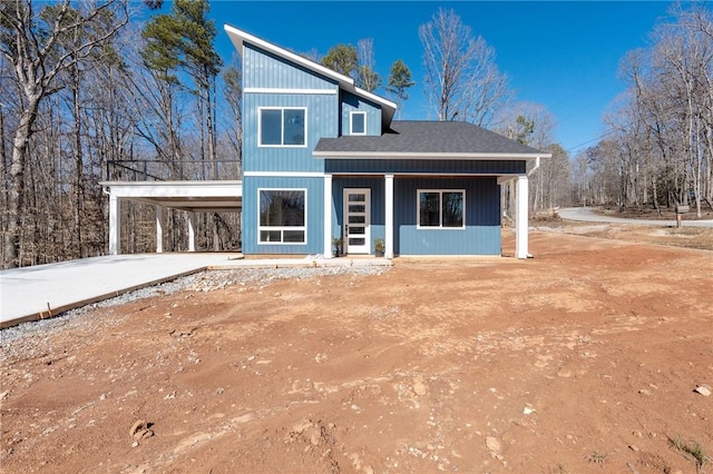 view of front of home featuring driveway, an attached carport, and roof with shingles