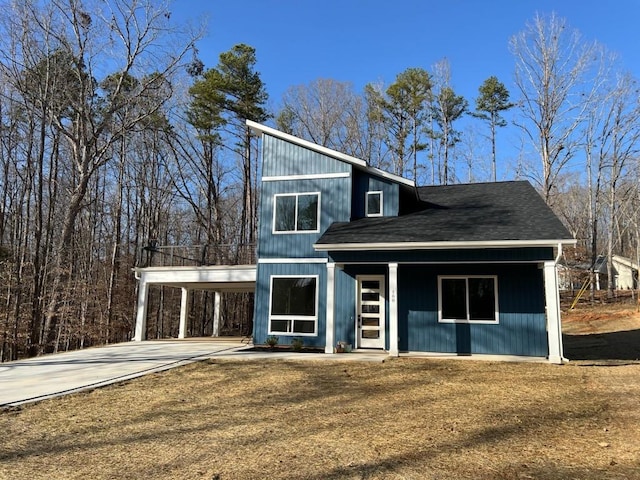 view of front of home with driveway, an attached carport, and roof with shingles