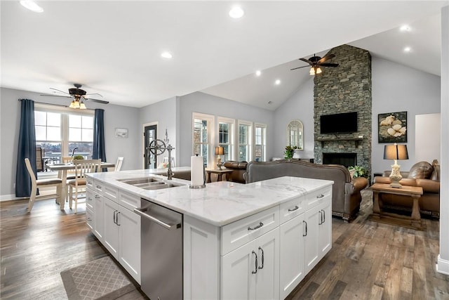 kitchen with sink, stainless steel dishwasher, a fireplace, light stone counters, and white cabinetry