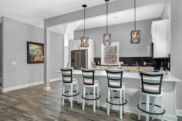 kitchen with stainless steel fridge, backsplash, dark wood-type flooring, pendant lighting, and white cabinets