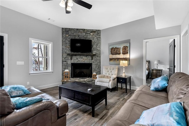 living room featuring ceiling fan, a fireplace, and hardwood / wood-style flooring