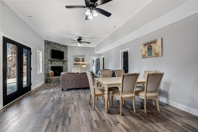 dining area with french doors, dark hardwood / wood-style floors, a stone fireplace, and ceiling fan