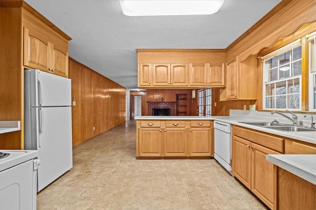 kitchen with kitchen peninsula, white appliances, sink, a fireplace, and wood walls