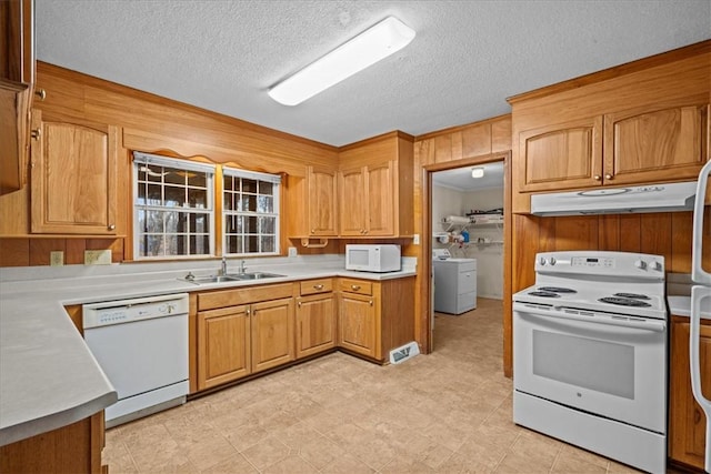 kitchen with a textured ceiling, wood walls, sink, and white appliances