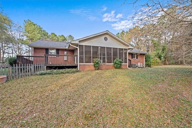 rear view of property with a lawn, a wooden deck, and a sunroom