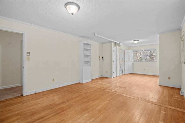 interior space featuring a textured ceiling, light wood-type flooring, and crown molding