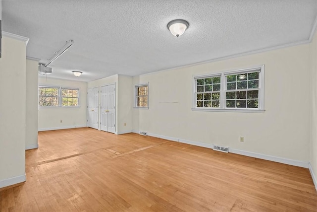 spare room with crown molding, hardwood / wood-style floors, and a textured ceiling