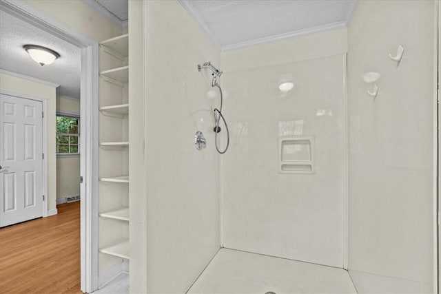 bathroom featuring a shower, a textured ceiling, hardwood / wood-style flooring, and crown molding