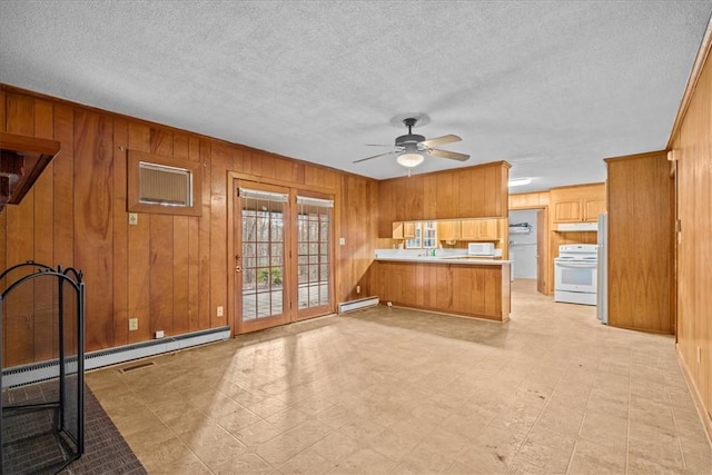 kitchen with a baseboard heating unit, kitchen peninsula, wood walls, a textured ceiling, and range