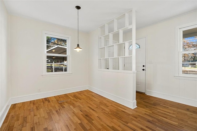 unfurnished dining area with hardwood / wood-style flooring and ornamental molding