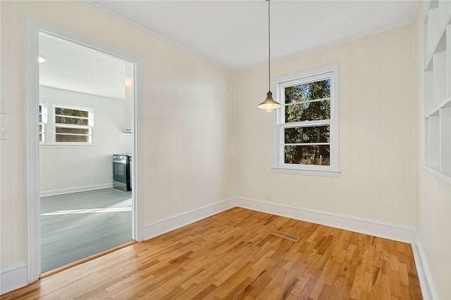 empty room featuring wood-type flooring and crown molding